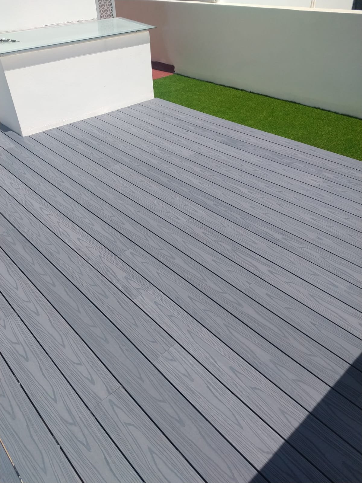 Piso deck gris para exterior junto a pasto sintético