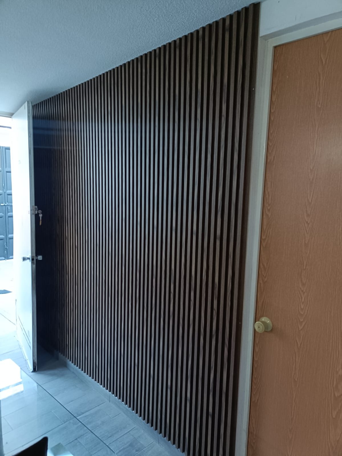 Lambrín de madera oscura en muro de entrada