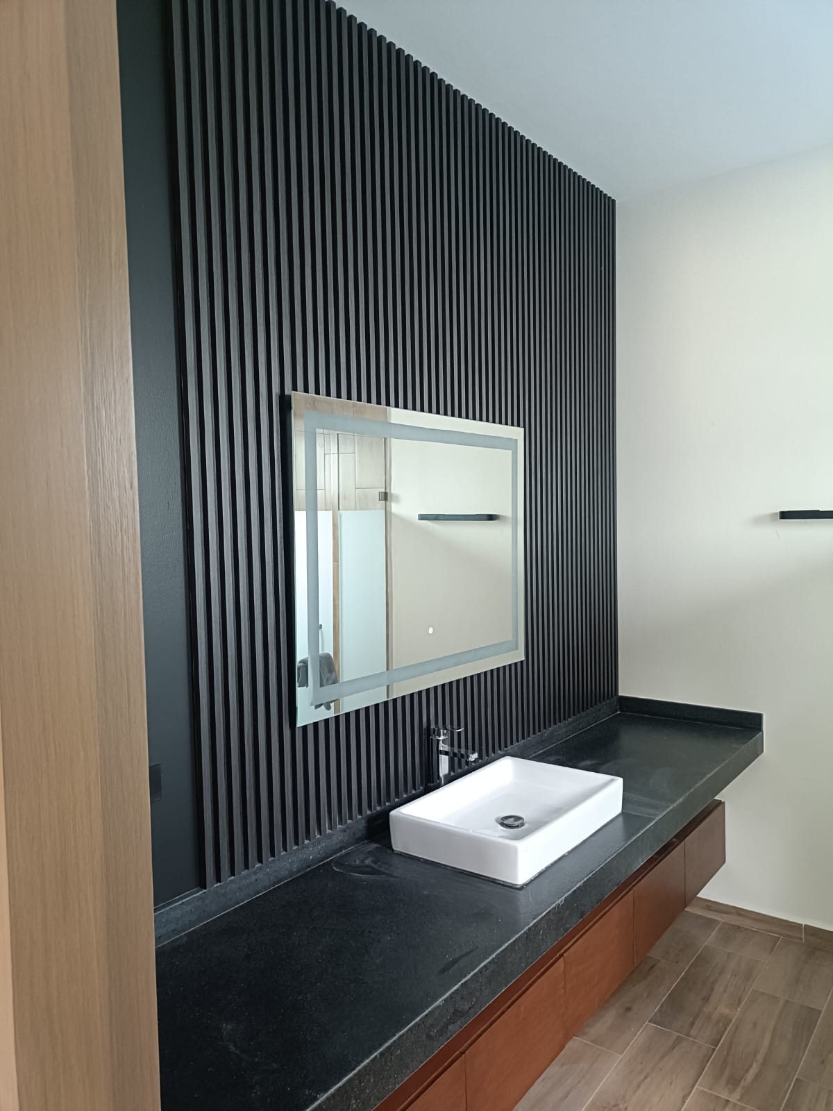 Lambrín negro en medio baño con espejo LED