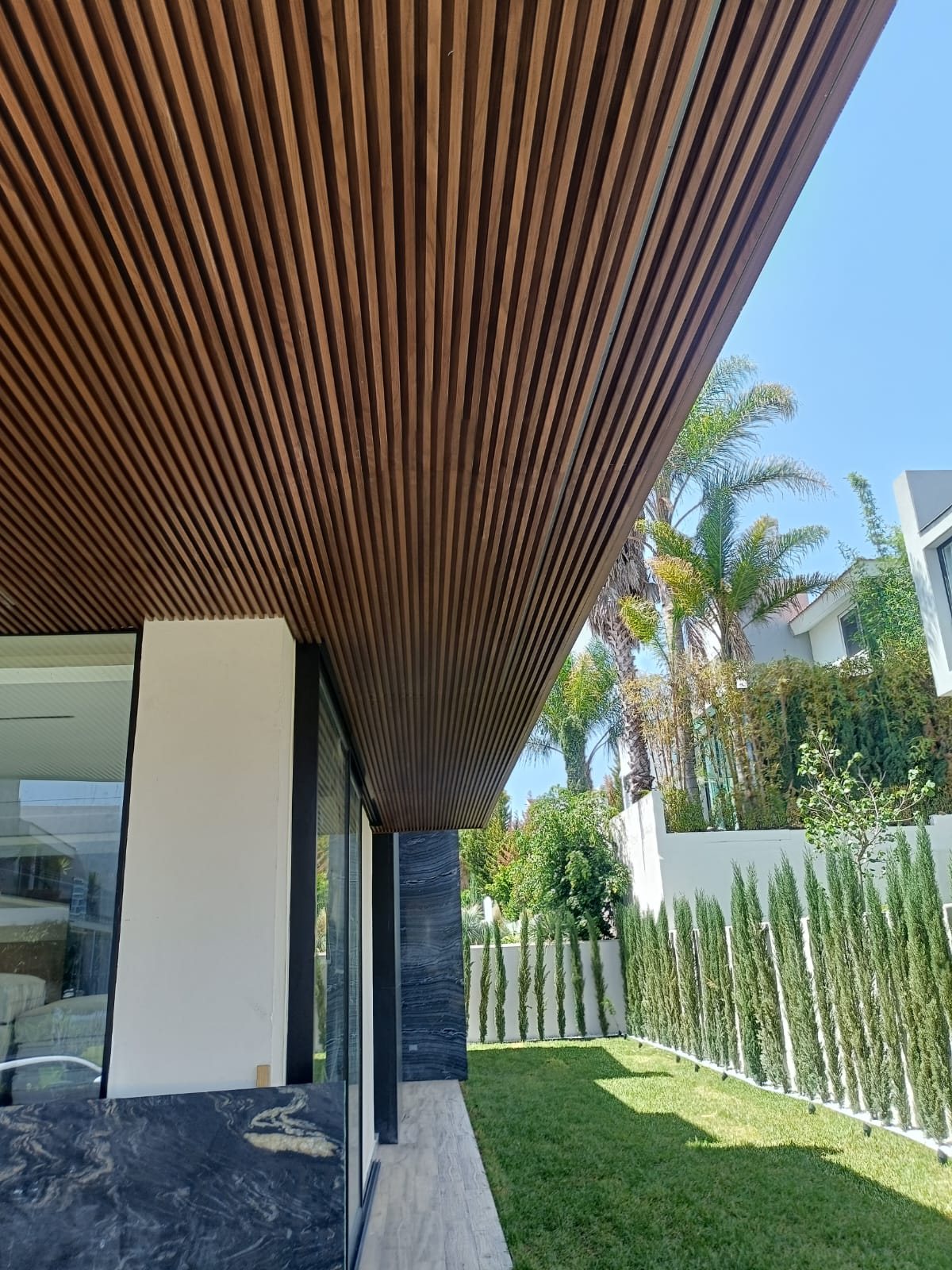 Lambrín de madera en plafón de terraza con jardín