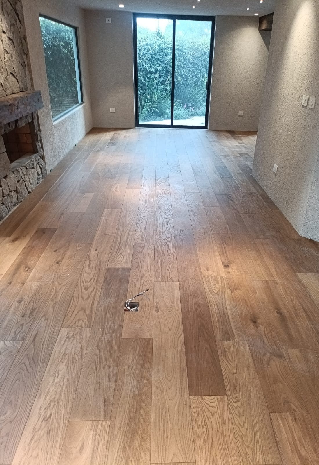 Piso de ingeniería en sala con chimenea de piedra