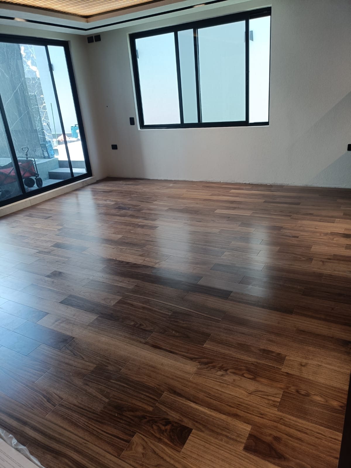Piso de ingeniería nogal en habitación con ventanales